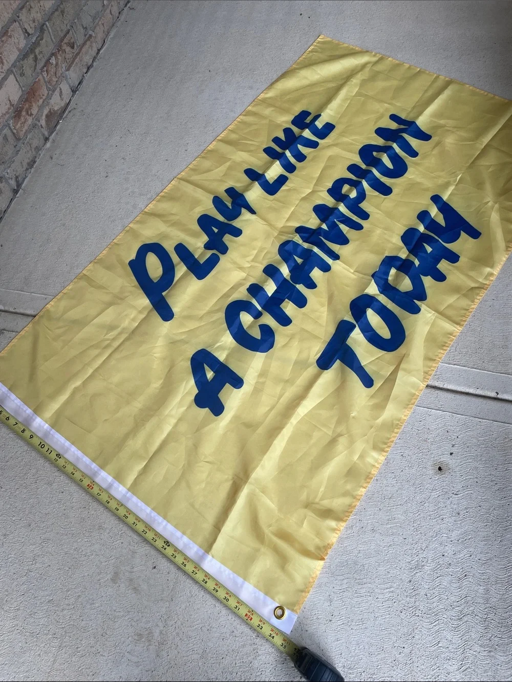 Play Like a Champion Today Yellow Banner with Blue Lettering and Grommet